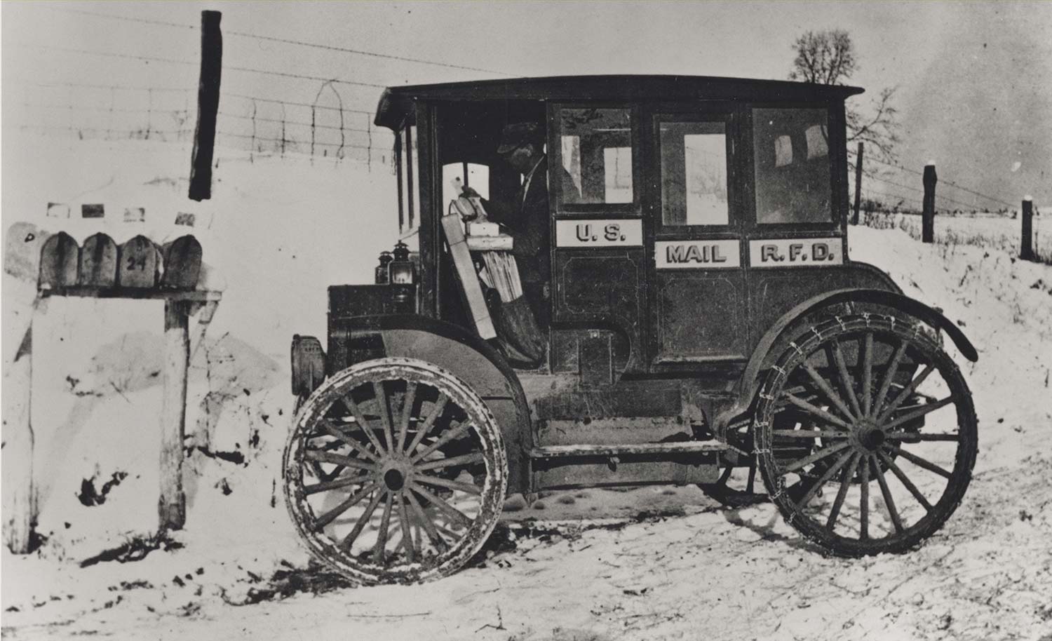 Rural_carrier_in_automobile_at_mailboxes,_c.1910